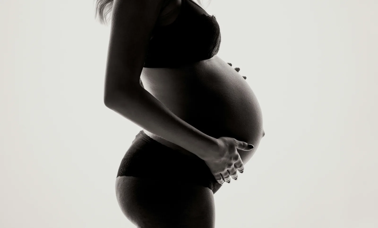 Pregnant woman cradling her belly in profile