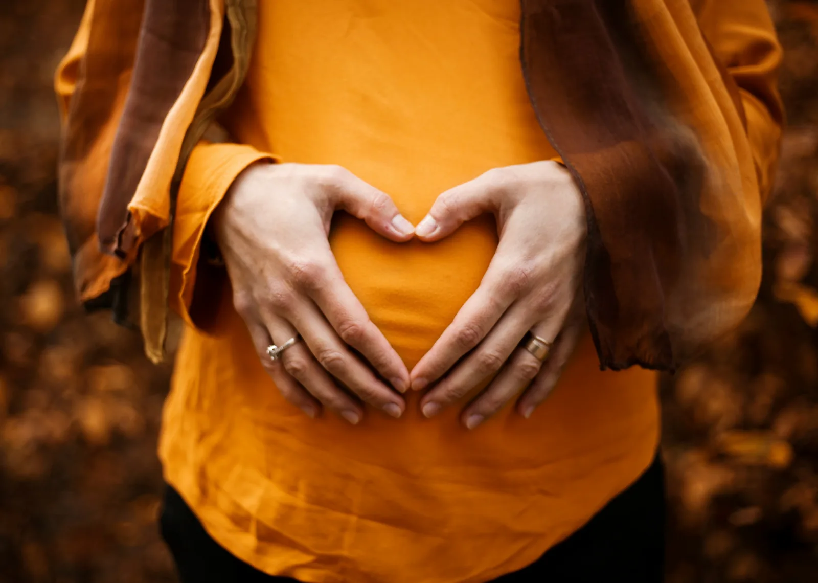 Hands forming a heart over a pregnant belly