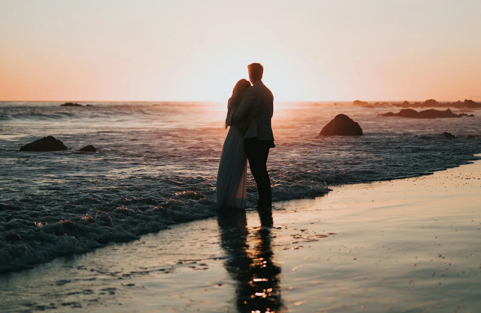 Couple embracing at the shoreline at sunset