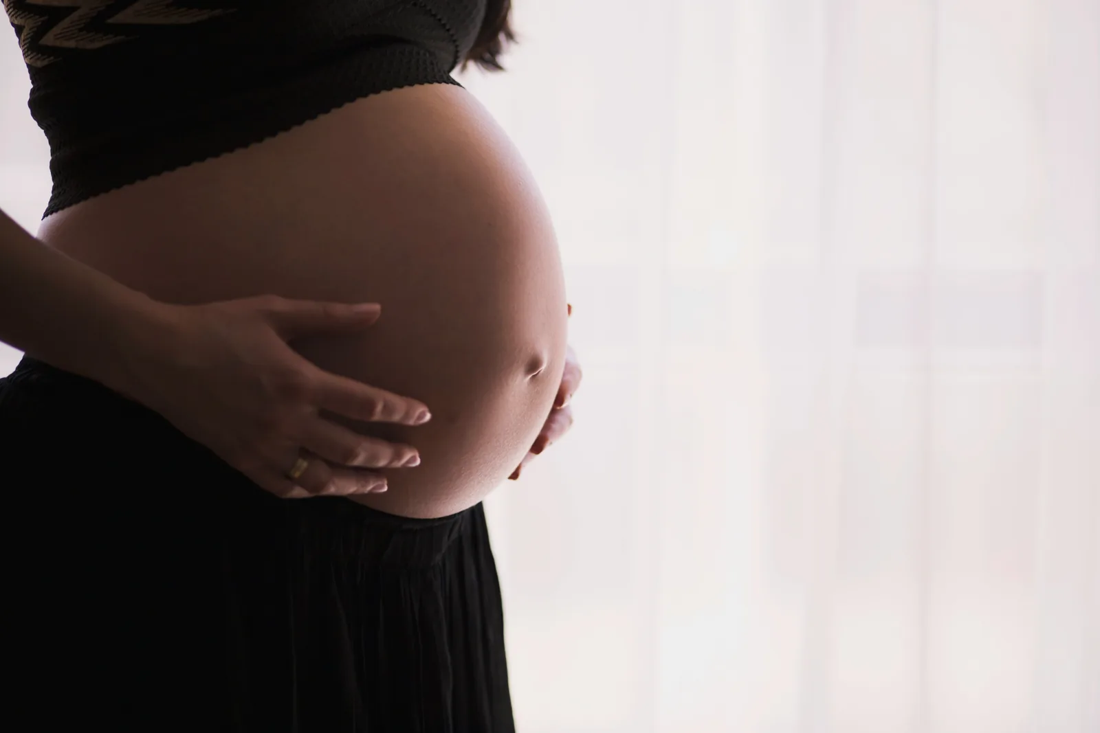 Close-up of a pregnant woman resting her hands on her belly