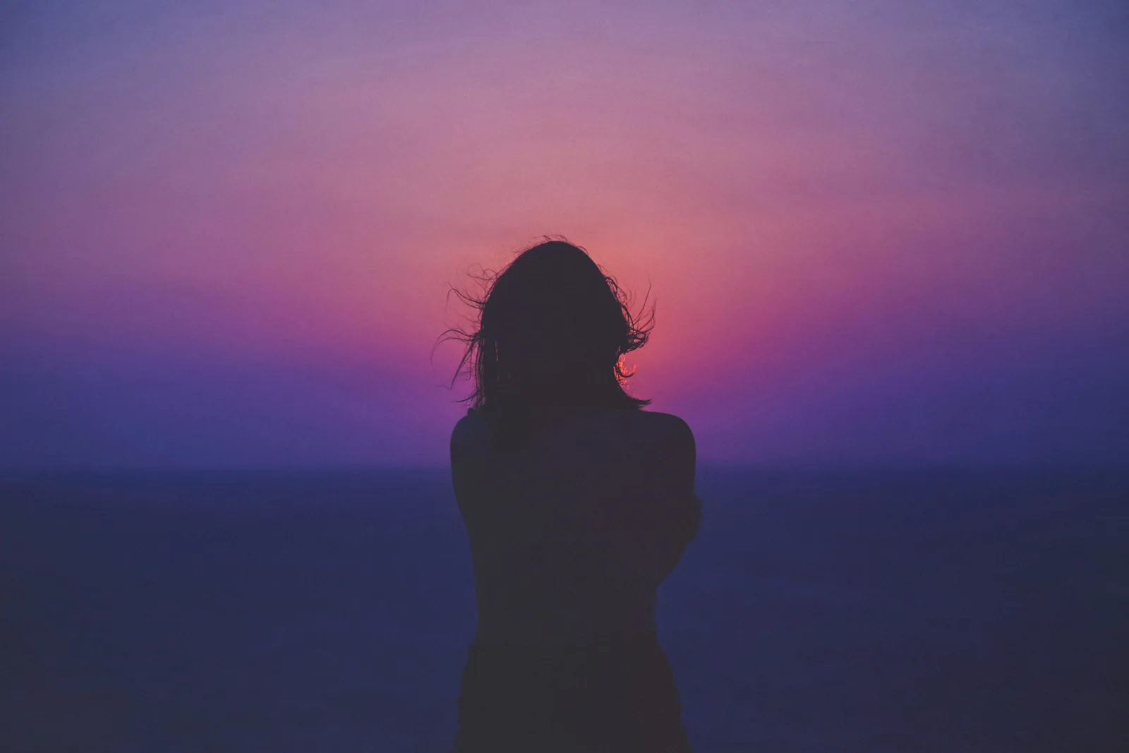 Silhouette of a woman against a purple sunset