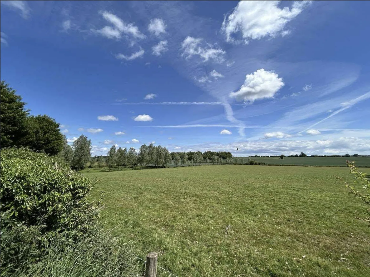 Fields near Rivenhall church beneath a blue sky